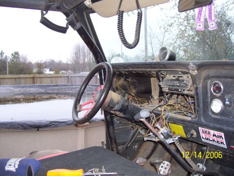 1978 Ford Bronco - The interior of a vehicle shows exposed wiring, a radio, and a steering wheel, with a gauge visible on the dashboard.