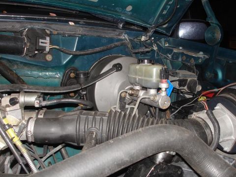 1996 Ford F-150 - Close-up view of the brake booster and master cylinder in a vehicle's engine compartment.