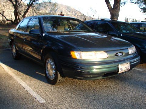 1993 Ford Taurus - Front 3/4 view of a dark green Ford Taurus parked in a lot.