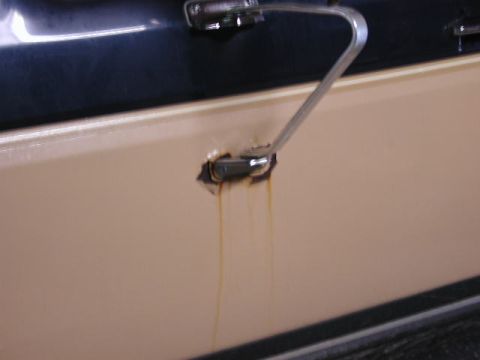 1988 Ford F-150 - Rusty fluid is dripping from the mounting point of a vehicle's door handle.