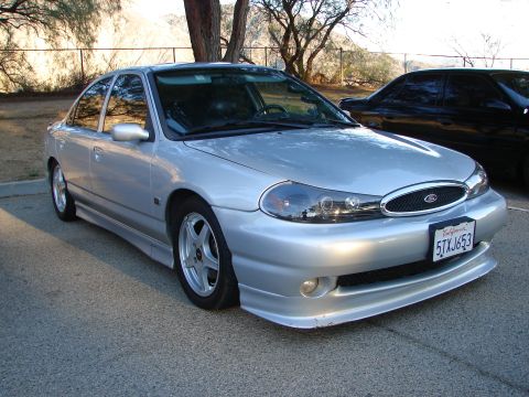 1993 Ford Taurus - Silver sedan with custom body kit and headlights parked outdoors. Another car is visible in the background.