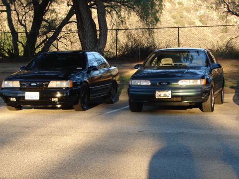 1993 Ford Taurus - Two Ford Taurus sedans are parked in a lot during the day.