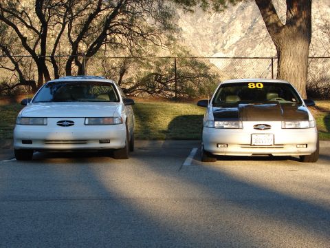 1993 Ford Taurus - Two 1993 Ford Taurus sedans are parked in a lot, one a carbon fiber hood and a yellow '80' sticker on the windshield.