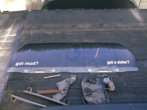 1989 Ford Bronco - Rear window with "got mud?" and "got a sister?" decals, along with various mechanical parts.