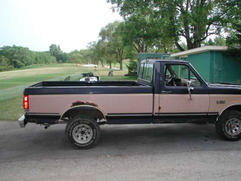 1988 Ford F-150 - This two-tone 1988 Ford F-150 pickup truck is seen from the side, showing some rust on the rear fender.