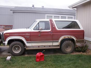 1984 Ford Bronco - Side view of a red and white Ford Bronco, showing its body style and condition.