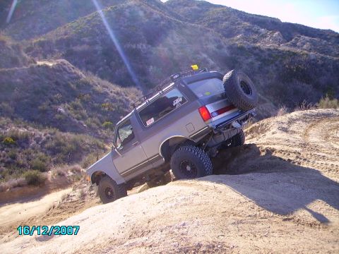 1990 Ford Bronco - Ford Bronco navigating an off-road trail on a sunny day.