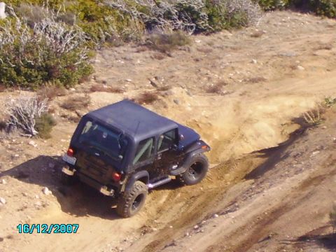 1990 Ford Bronco - Jeep Wrangler navigating a challenging off-road trail on a sunny day.
