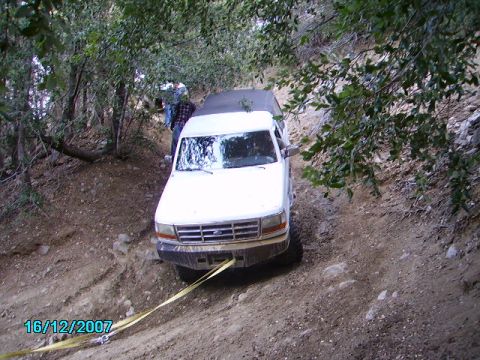 1990 Ford Bronco - This Ford Bronco appears to be stuck on a steep, wooded trail, with a tow strap attached to the front bumper.