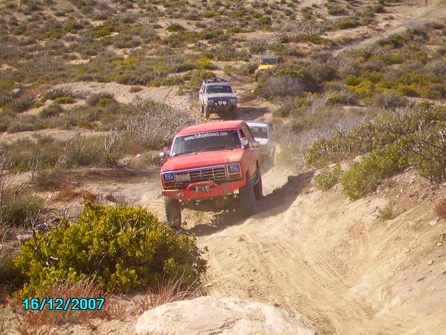 Red off-road SUV with custom bumper driving on a dirt trail