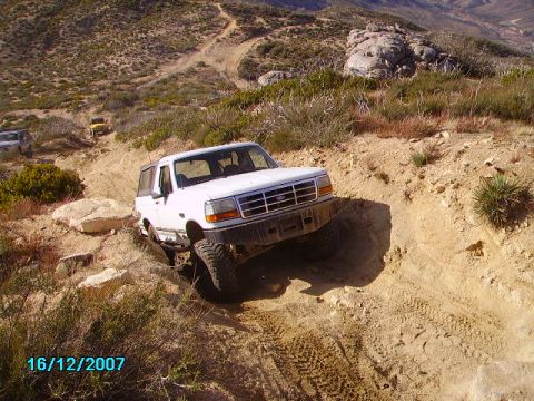 1990 Ford Bronco - White Ford Bronco tackling a steep, rocky off-road trail in a mountainous area.