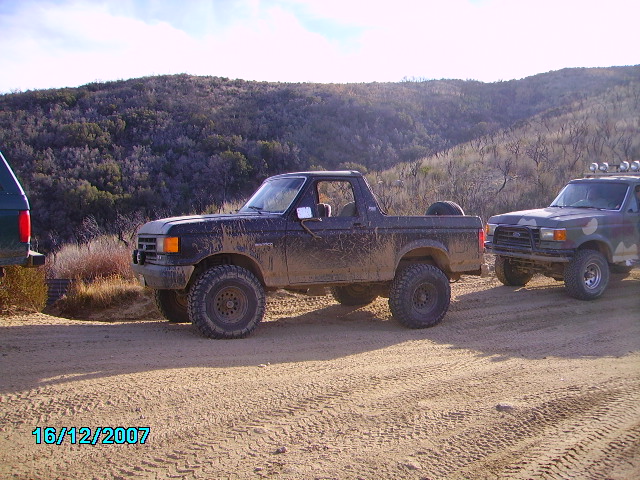 Black 1990 Ford Bronco side view, muddy, with spare tire on back