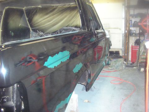1987 Ford Bronco - A black SUV body is undergoing repairs in a garage, with turquoise primer visible on the fender.