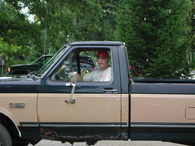 Two-tone black and tan Ford F-150 pickup with a driver seated behind the wheel