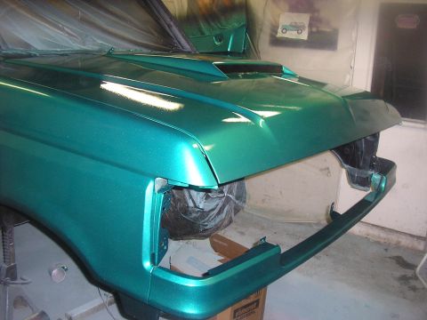 1987 Ford Bronco - The front end of a green metallic SUV, possibly undergoing restoration, is shown from the front.