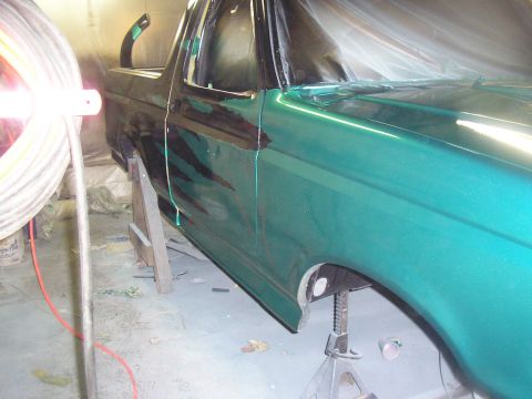 1987 Ford Bronco - A green SUV is shown in a workshop, possibly being prepped for or undergoing a paint job, with visible repair work.