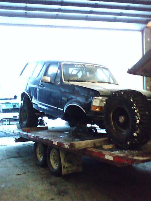 1992 Ford Bronco - Ford Bronco loaded onto a trailer, modified with large off-road tires.