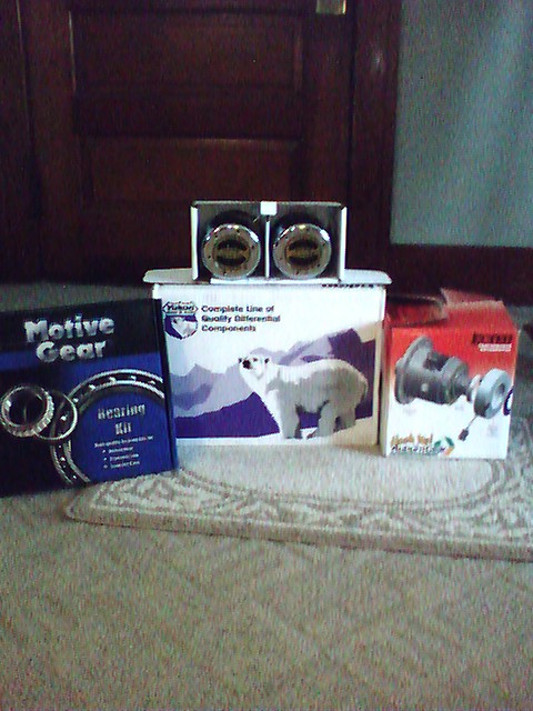 1992 Ford Bronco - Several boxes of automotive parts, including a bearing kit and differential components, are displayed on a rug.