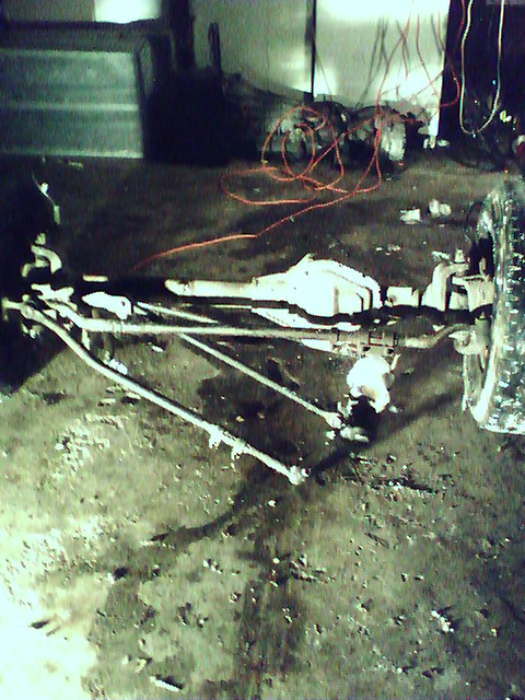 1992 Ford Bronco - Close-up of vehicle chassis components, including the front axle and suspension, on a workshop floor.