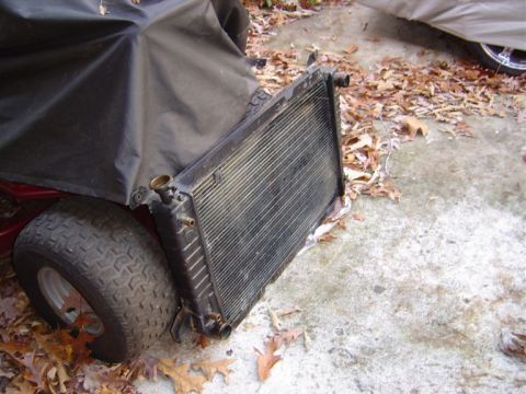 1986 Ford Bronco - A radiator is shown outdoors, partially covered by a black tarp and near a tire.