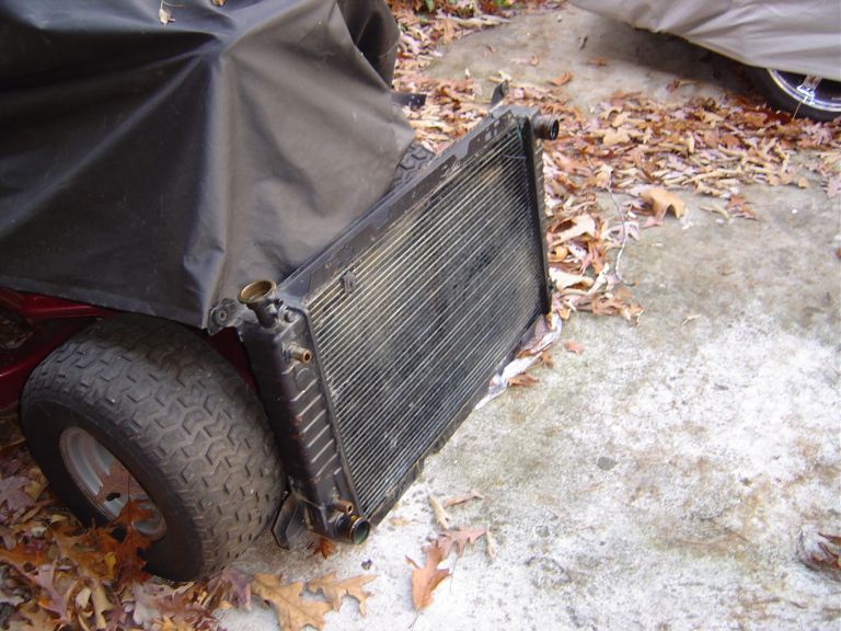 Radiator resting on the ground next to a covered object with a tire