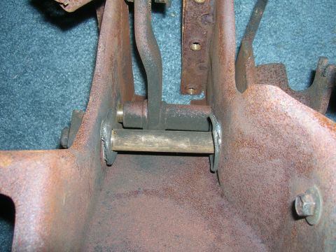 1979 Ford Bronco - This photo shows a rusty metal bracket assembly with a pivot pin, likely from a vehicle's interior mechanism.