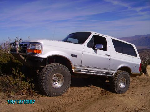 1990 Ford Bronco - This white Ford Bronco, likely from the early to mid-1990s, is equipped for off-road use with a custom bumper and aggressive tires.