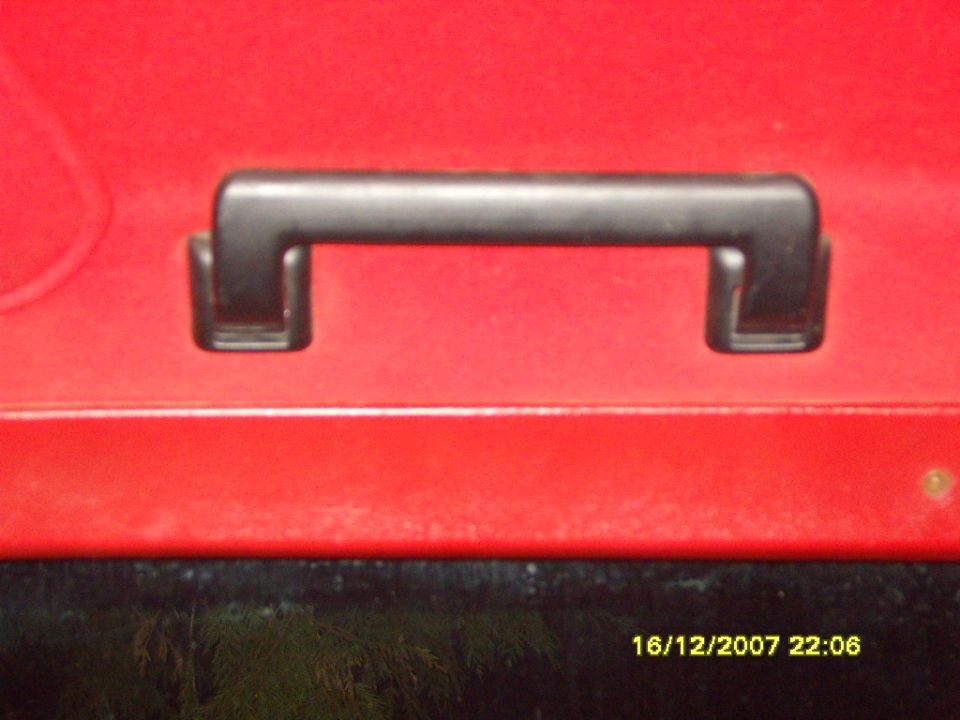 Black plastic grab handle mounted on a red painted interior panel, dated 2007 photo