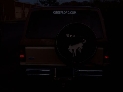 1984 Ford Bronco II - The rear of a Ford Bronco II is visible, complete with a spare tire cover and a website sticker on the rear window.