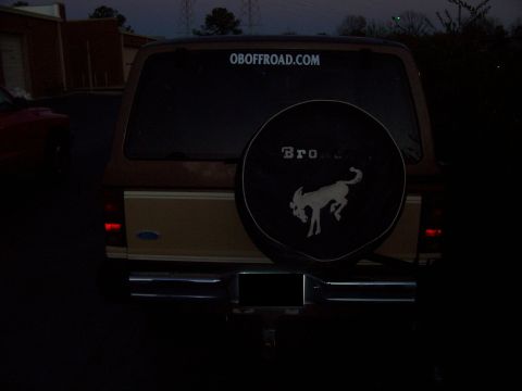 1984 Ford Bronco II - Rear view of a brown 1984 Ford Bronco II, a spare tire cover with the Bronco logo and an "OBOFFROAD.COM" sticker on the rear window.