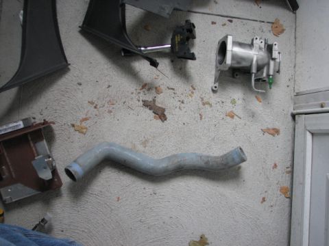 2003 Ford Crown Victoria - Various automotive parts are laid out on a textured concrete floor, with some scattered leaves visible.