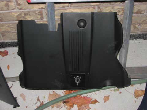 2003 Ford Crown Victoria - This is a black engine cover with a V8 emblem and vertical lines, likely a replacement part.