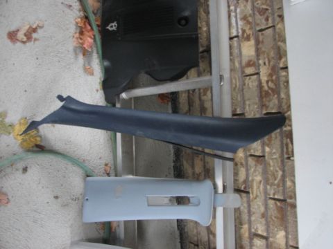 2003 Ford Crown Victoria - Several plastic car interior trim pieces are shown, including a dark gray A-pillar trim and a light gray piece with a rectangular cutout.