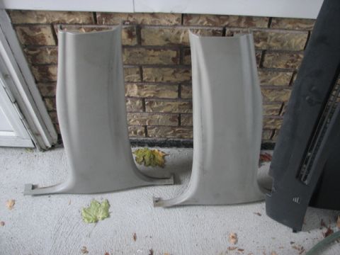 2003 Ford Crown Victoria - Two interior trim pillars and a black dashboard piece are displayed on a concrete surface with fallen leaves.