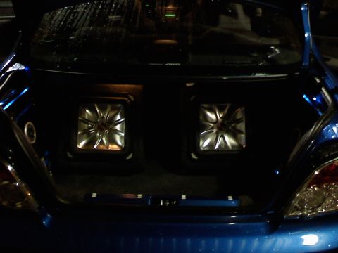 2007 Subaru Impreza - The trunk of a blue car is open, revealing two square subwoofers with silver accents.