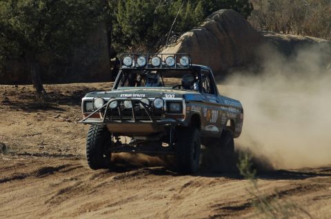 1978 Ford Bronco - This modified truck is competing in an off-road race, kicking up a cloud of dust as it drives.