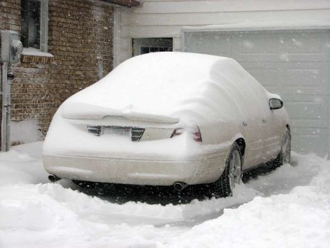 2003 Ford Crown Victoria - A 2003 Ford Crown Victoria is buried in snow next to a garage during a winter storm.