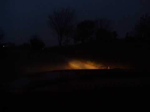 1986 Ford Bronco - Headlights cut through the darkness on a rural road, illuminating the path ahead.