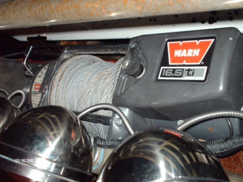 1982 Ford F-100 - A Warn 16.5ti winch mounted low behind a bumper, its drum spooled with gray synthetic rope and armored cable loom running across the front.…