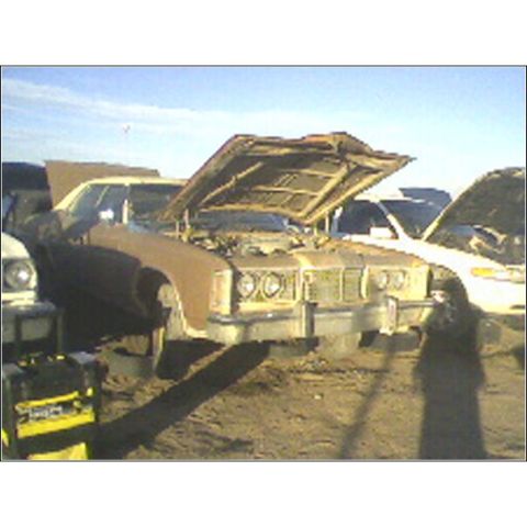 1973 Ford Ranchero - Two cars sit in a junkyard, hoods raised, under a clear blue sky.