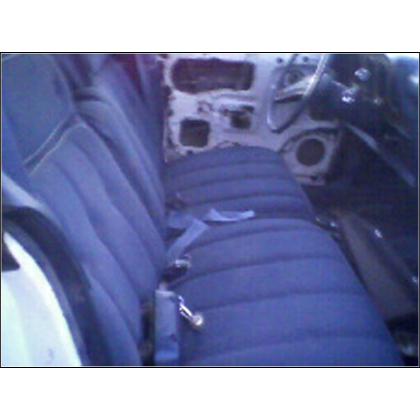 Interior view of a car with blue bench seat and seatbelts, showing door panel removed and dashboard