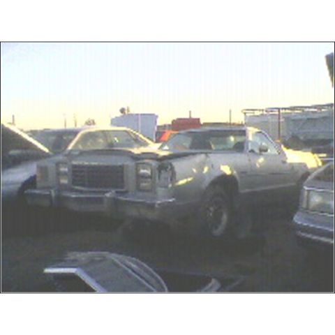 1973 Ford Ranchero - Junkyard scene with a damaged pickup truck in the foreground.