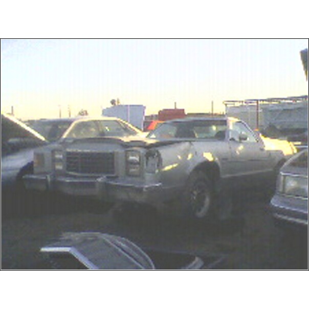 Junkyard pickup truck with damaged front end, parked next to other vehicles