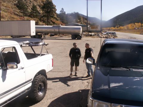 1986 Ford Bronco - Two men stand between a white pickup truck and a black SUV in a scenic, mountainous area.