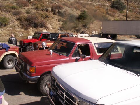 1986 Ford Bronco - Several vehicles are parked together, including a red Ford Bronco and a white truck.