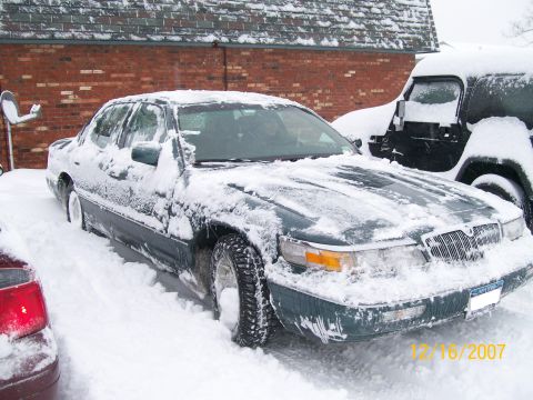 1995 Mercury Grand Marquis - A 1995 Mercury Grand Marquis is buried in snow, with another vehicle visible behind it.