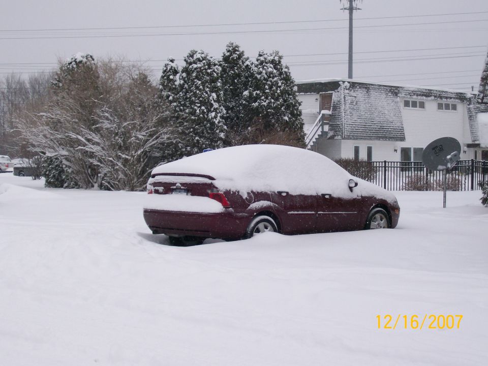 Maroon sedan buried in snow, rear quarter view. Date stamp reads 12/16/2007
