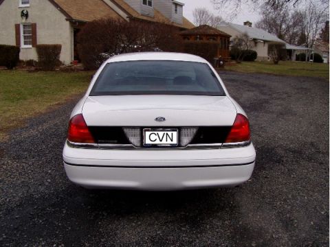 1999 Ford Crown Victoria - White Ford Crown Victoria sedan parked in a driveway, showing its rear end and taillights.