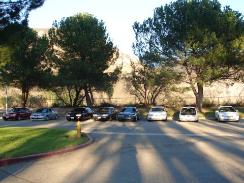1992 Ford Taurus - A row of sedans, including a 1992 Ford Taurus, are parked in a lot with trees and hills in the background.