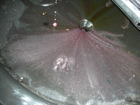 1992 Ford Crown Victoria - A close-up view of a transmission fluid leak, with red fluid and metallic debris visible.